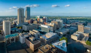 Aerial View Of Downtown Omaha, Nebraska Showcasing Modern Skyscrapers And Historic Buildings Under A Clear Blue Sky.