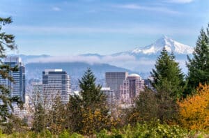 Scenic View Of Portland, Oregon With Downtown Buildings And Mount Hood In The Background, Covered By Clouds And Mist.