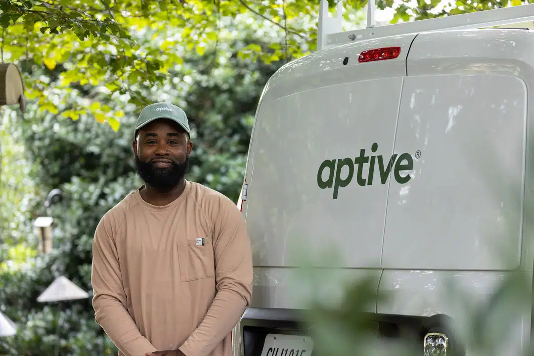 Aptive Pest Control  Specialist Standing And Smiling In Front Of An Aptive Van.