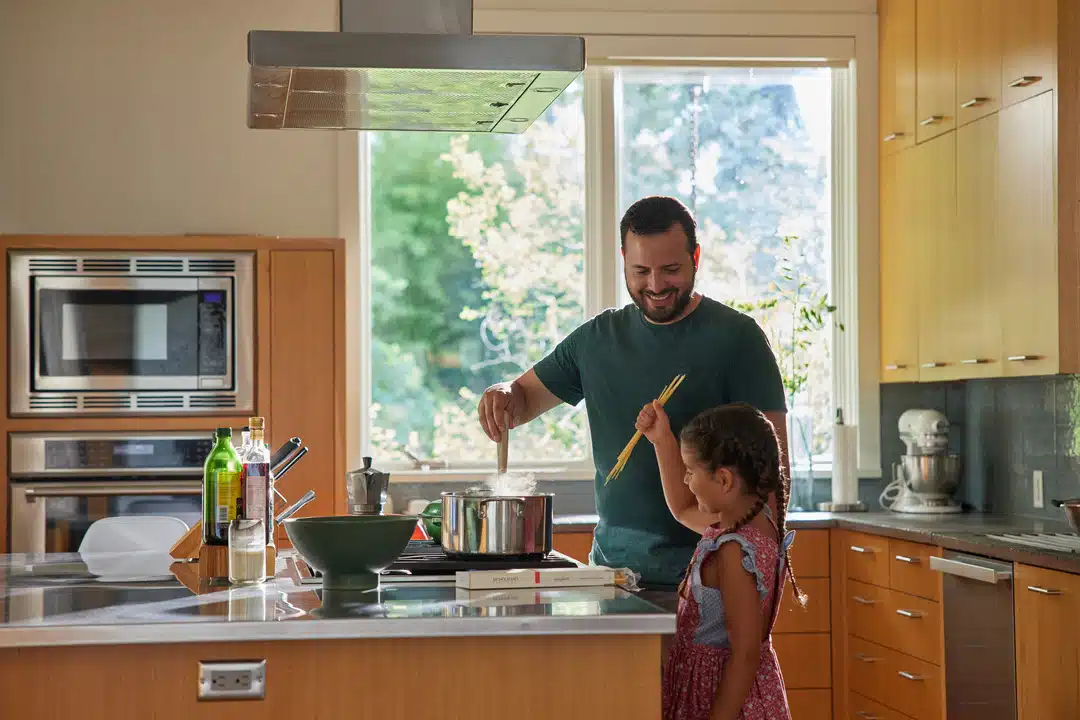 A Father And Daughter Cooking Together In A Bright And Modern Kitchen.